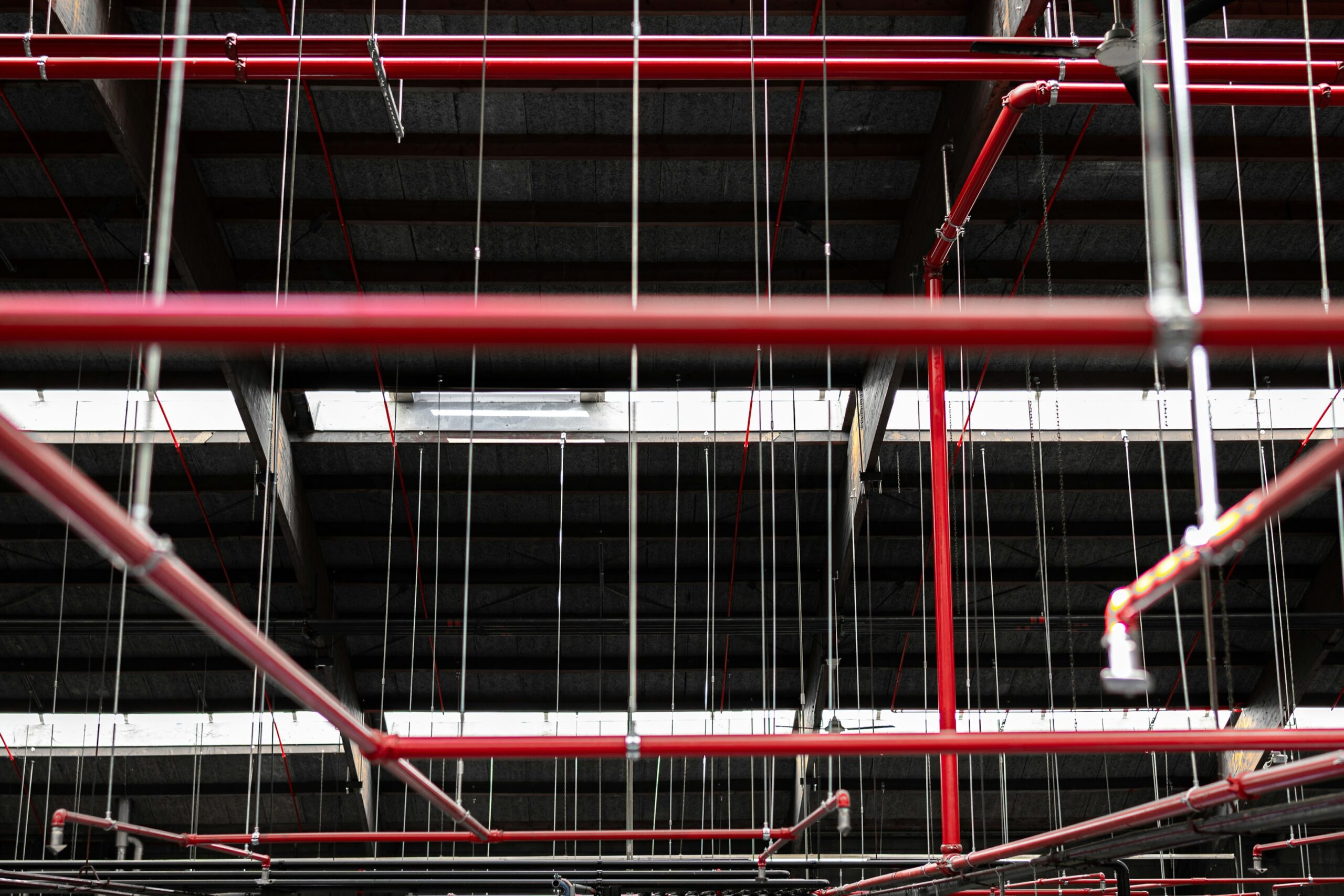 Red sprinkler pipes suspended across an industrial ceiling